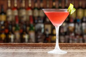 colorful cocktail on bar with liquor bottles in background